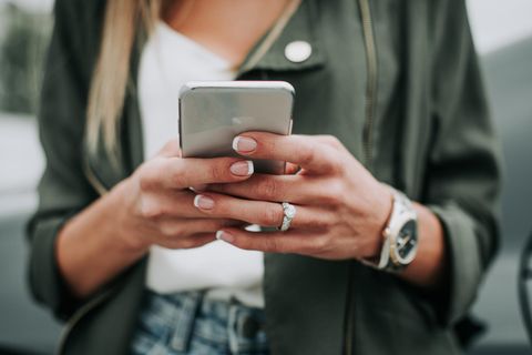 Eine junge Frau hält ein Smartphone in ihrer Hand