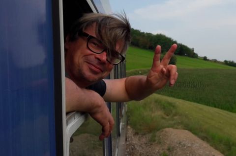 Jaroslav Rudiš winkt aus dem Fenster eines fahrenden Zugs
