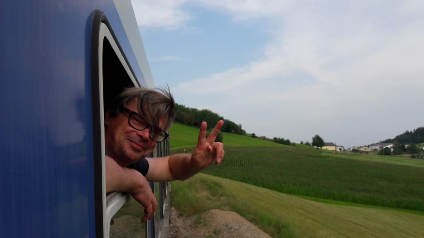 Jaroslav Rudiš winkt aus dem Fenster eines fahrenden Zugs