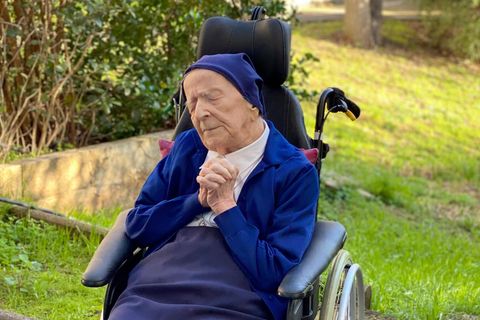 Schwester André sitzt betend in ihrem Rollstuhl.