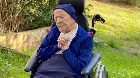 Schwester André sitzt betend in ihrem Rollstuhl.
