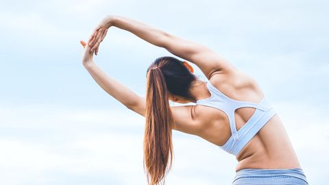 Junge Frau in Gymnastikkleidung stretcht ihren Rücken