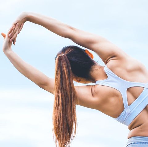 Junge Frau in Gymnastikkleidung stretcht ihren Rücken