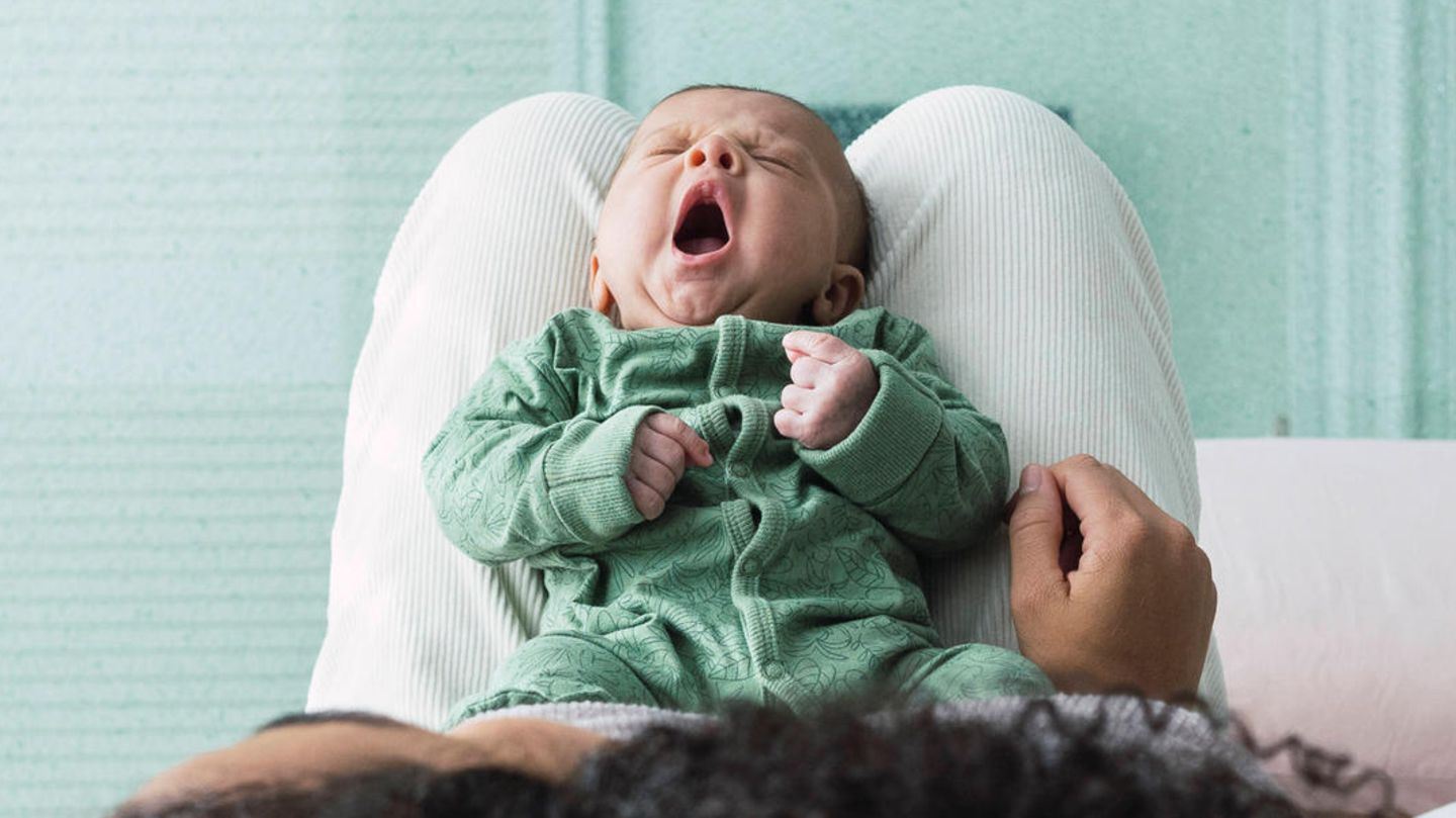 A baby yawns on its mother's lap.  In Germany, there was a high birth rate in the second year of Corona
