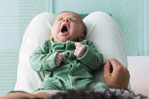 Ein Baby gähnt auf dem Schoß seiner Mutter. In Deutschland gab es im zweiten Corona-Jahr ein Geburten-Hoch