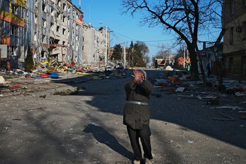 Eine Frau hebt abwehrend die Hand auf einer Straße von Mariupol