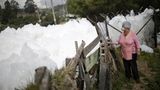 Eine Frau sieht sich den Schaum aus geringer Distanz an. Die Schaumschicht ist menschenhoch aufgetürmt.