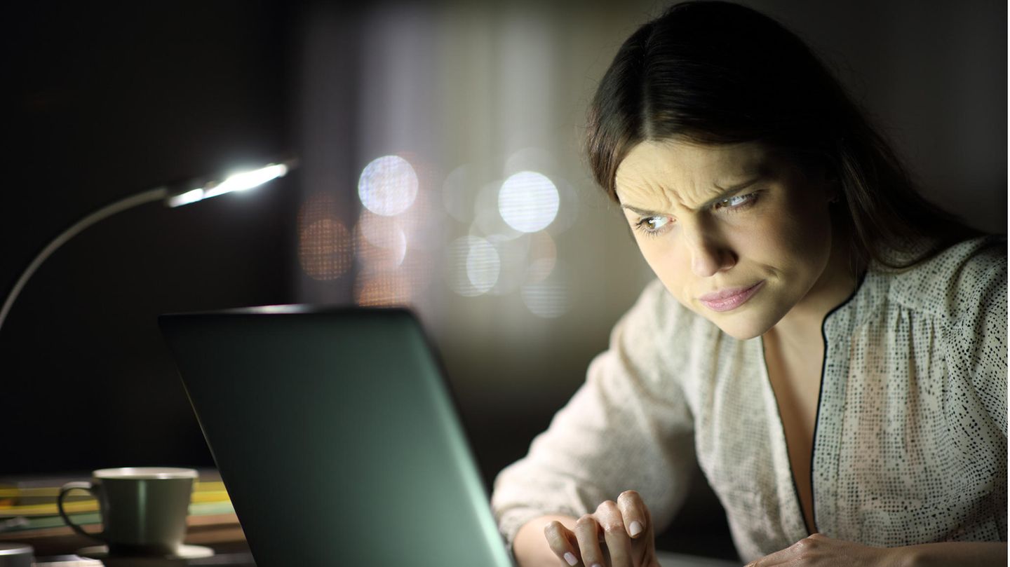 Eine junge Frau schaut skeptisch auf ihren Rechner