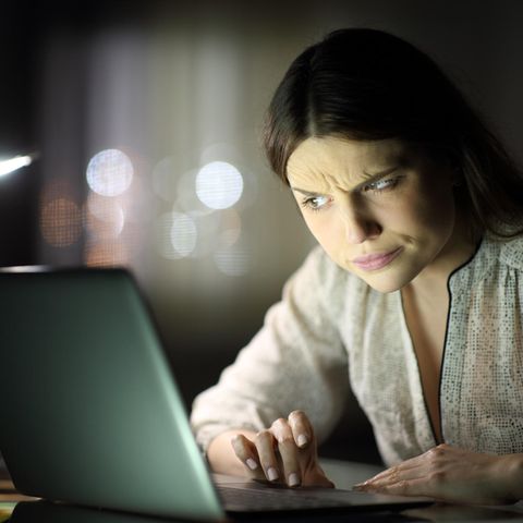 Eine junge Frau schaut skeptisch auf ihren Rechner