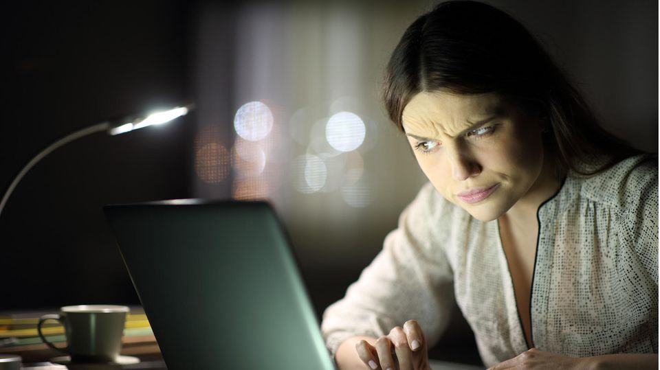 A young woman is looking skeptical at her computer