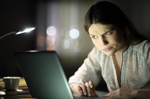 Eine junge Frau schaut skeptisch auf ihren Rechner