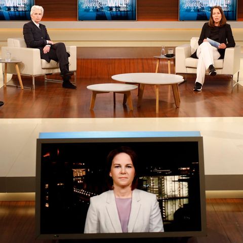 In einem in Blau und Creme gehaltenem TV-Studio sitzen drei Frauen und zwei Männer auf hellen Sesseln mit Abstand