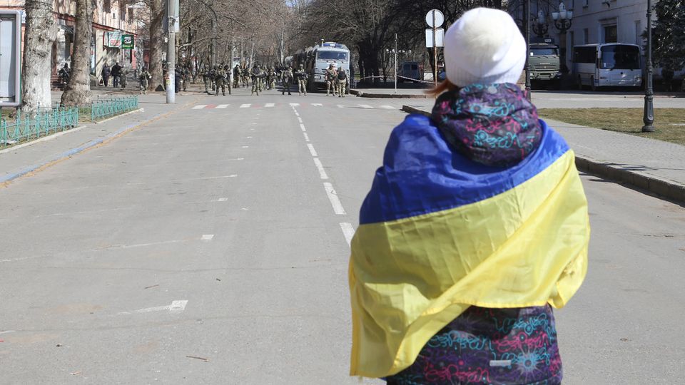 Eine Frau mit ukrainischer Fahne während einer Demonstration gegen die russische Besatzung
