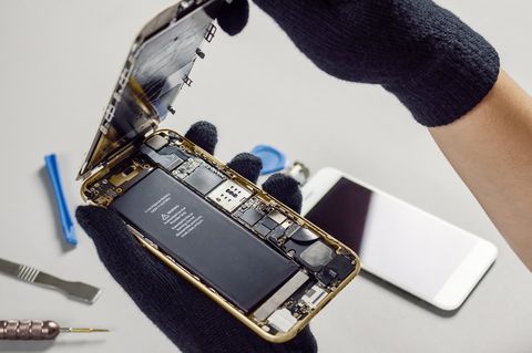 Eine Hand hält ein Smartphone und einen Akku fest