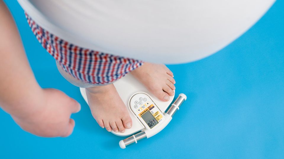 Mann steht auf der Waage und ist übergewichtig