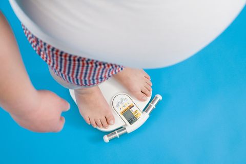 Mann steht auf der Waage und ist übergewichtig