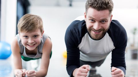 Sport und Gesundheit: Ein Junge und ein Mann machen gemeinsam Planks