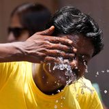 Mann kühlt sich auf einem Marktplatz mit Wasser ab