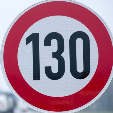 An der Autobahn steht ein Verkehrsschild mit der Geschwindigkeitsangabe von 130 Stundenkilometern