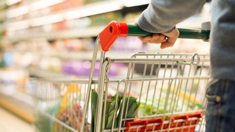 Mann schiebt Einkaufswagen durch einen Supermarkt