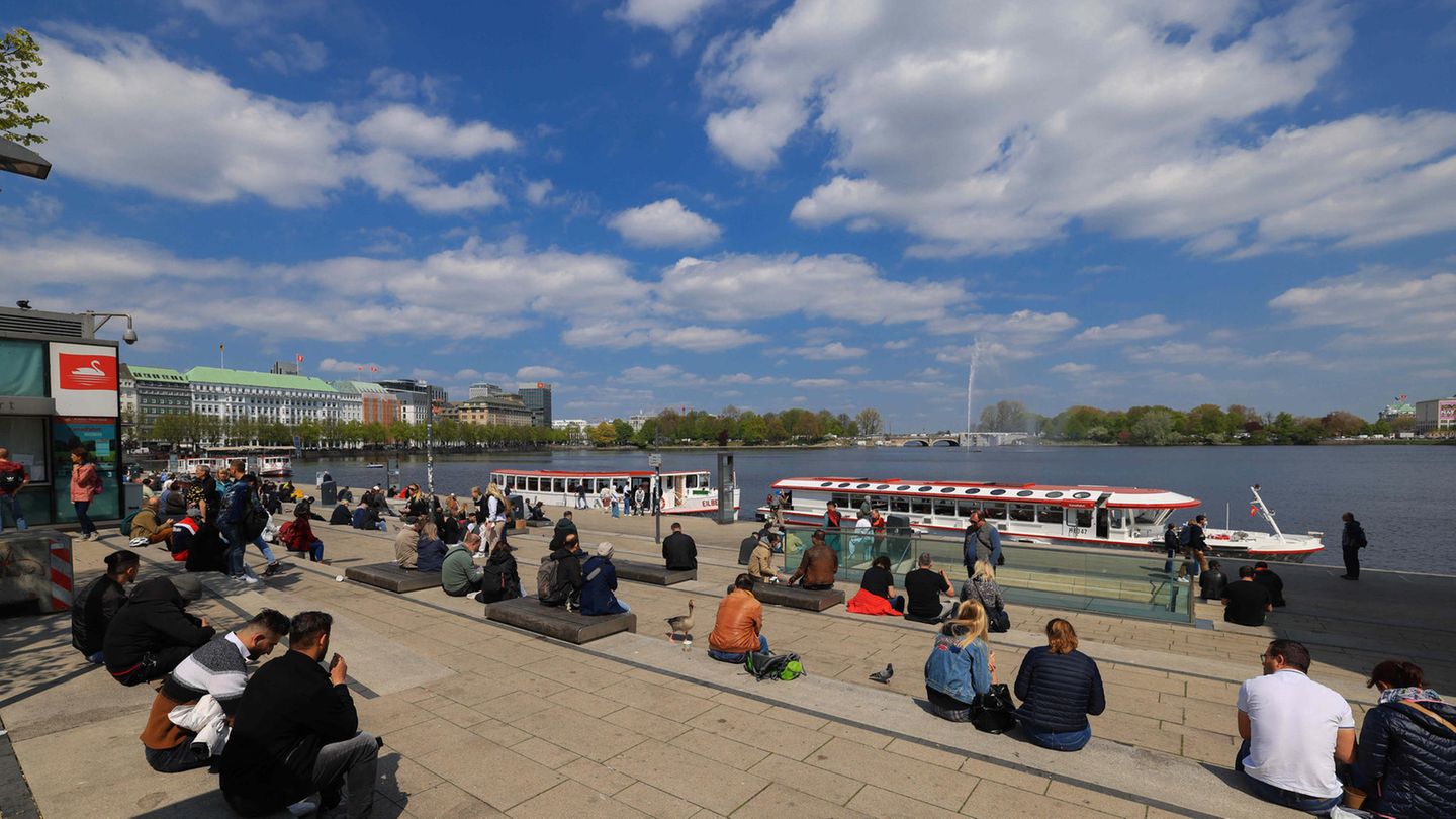 bei schönem Wetter sitzen Menschen an der Alster in Hamburg