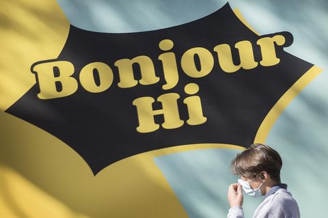 Passant vor einem Schild mit der Aufschrift "Bonjour – Hi"