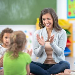 Eine lachende Lehrerin im Kreis kleiner Kinder
