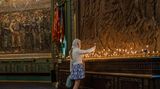 Eine Frau entzündet eine Kerze in einer Kirche
