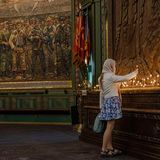 Eine Frau entzündet eine Kerze in einer Kirche