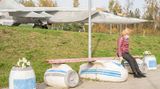 Eine Frau sitzt auf einer Bank in Flugzeugform