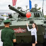 Eine junge Frau posiert mit einem Luftballon vor einem Panzer