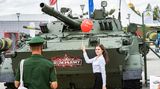 Eine junge Frau posiert mit einem Luftballon vor einem Panzer