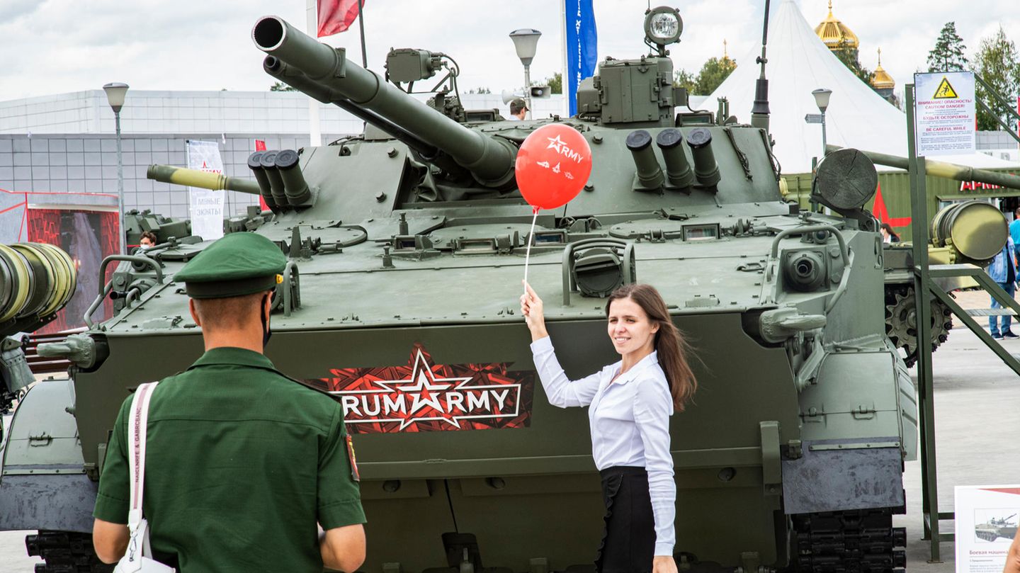 Eine junge Frau posiert mit einem Luftballon vor einem Panzer