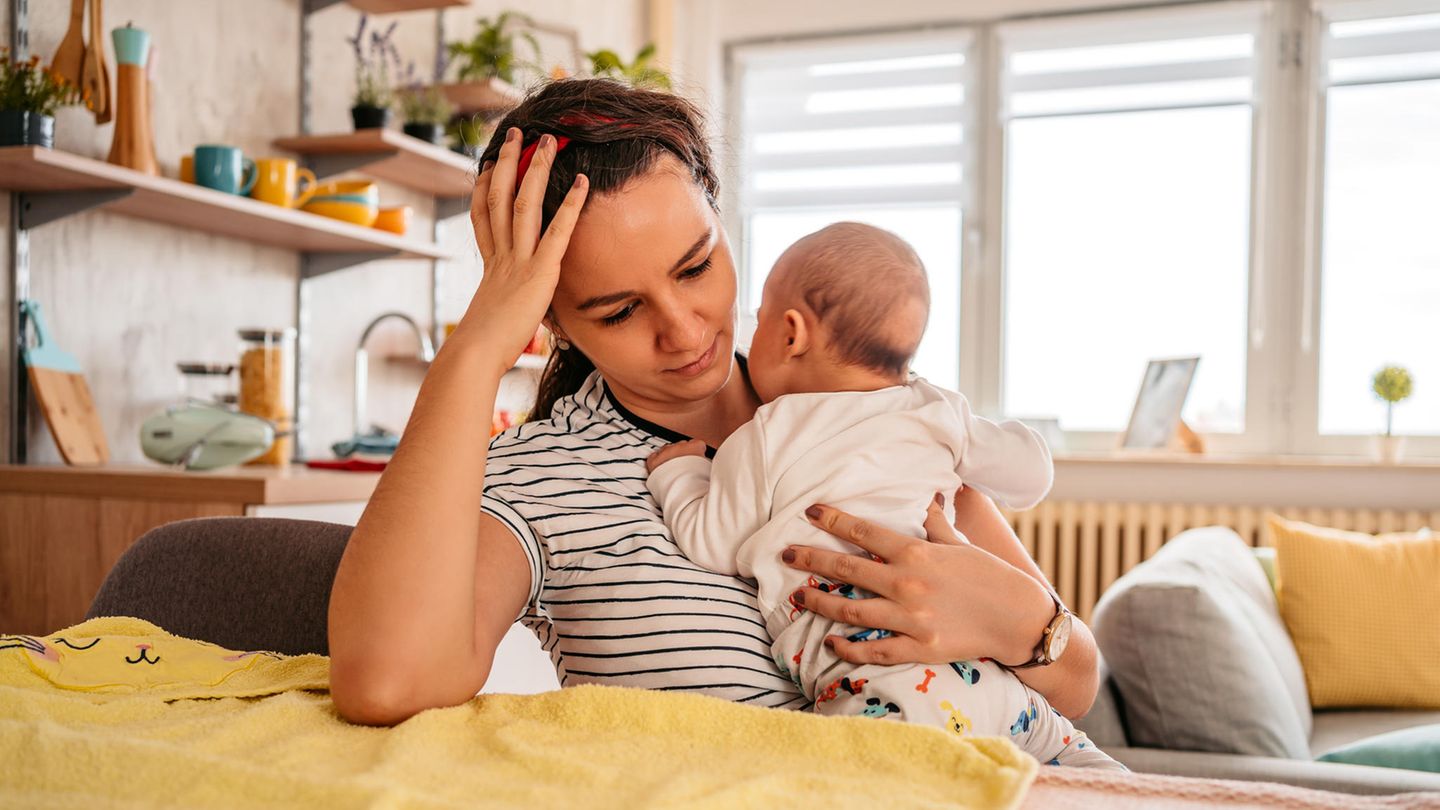 Eine Mutter hält ihr Baby auf dem arm und sieht nachdenklich dabei aus. Eine Mutter hält ihr Baby auf dem arm und sieht nachdenklich dabei aus.
