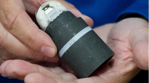Ein Mitarbeiter einer Munitionsentsorgungsfirma zeigt scharfe aber gesicherte Streumunition