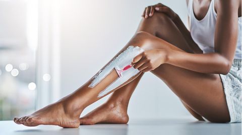Eine Frau rasiert ihre Beine