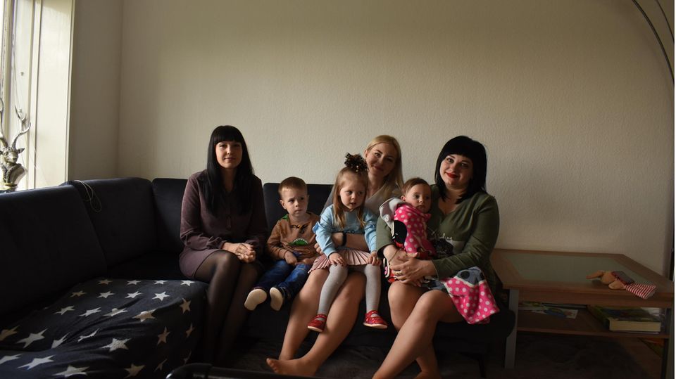 Drei Mütter aus der Ukraine sitzen mit ihren Kindern auf einem Sofa