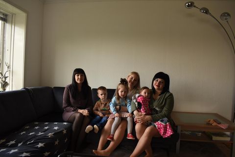 Drei Mütter aus der Ukraine sitzen mit ihren Kindern auf einem Sofa