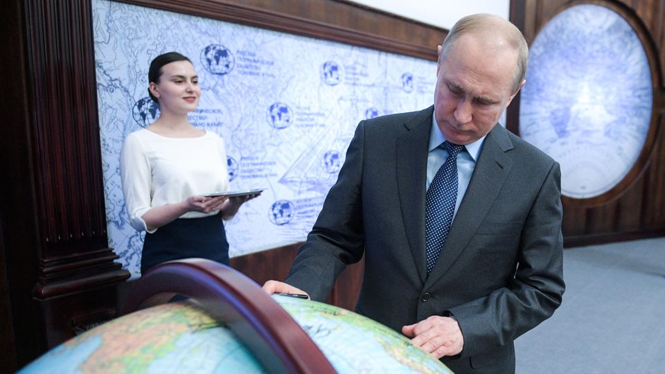 Wladimir Putin schaut auf einen Globus