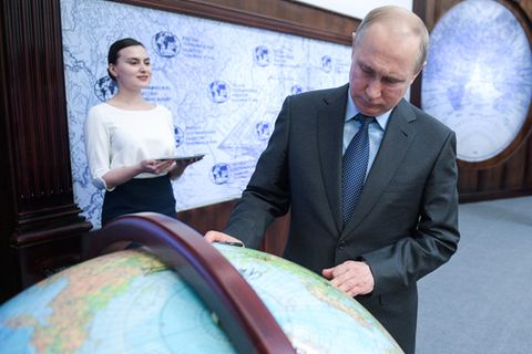 Wladimir Putin schaut auf einen Globus