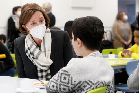 Yvonne Gebauer trägt eine Maske und spricht mit einem Kind