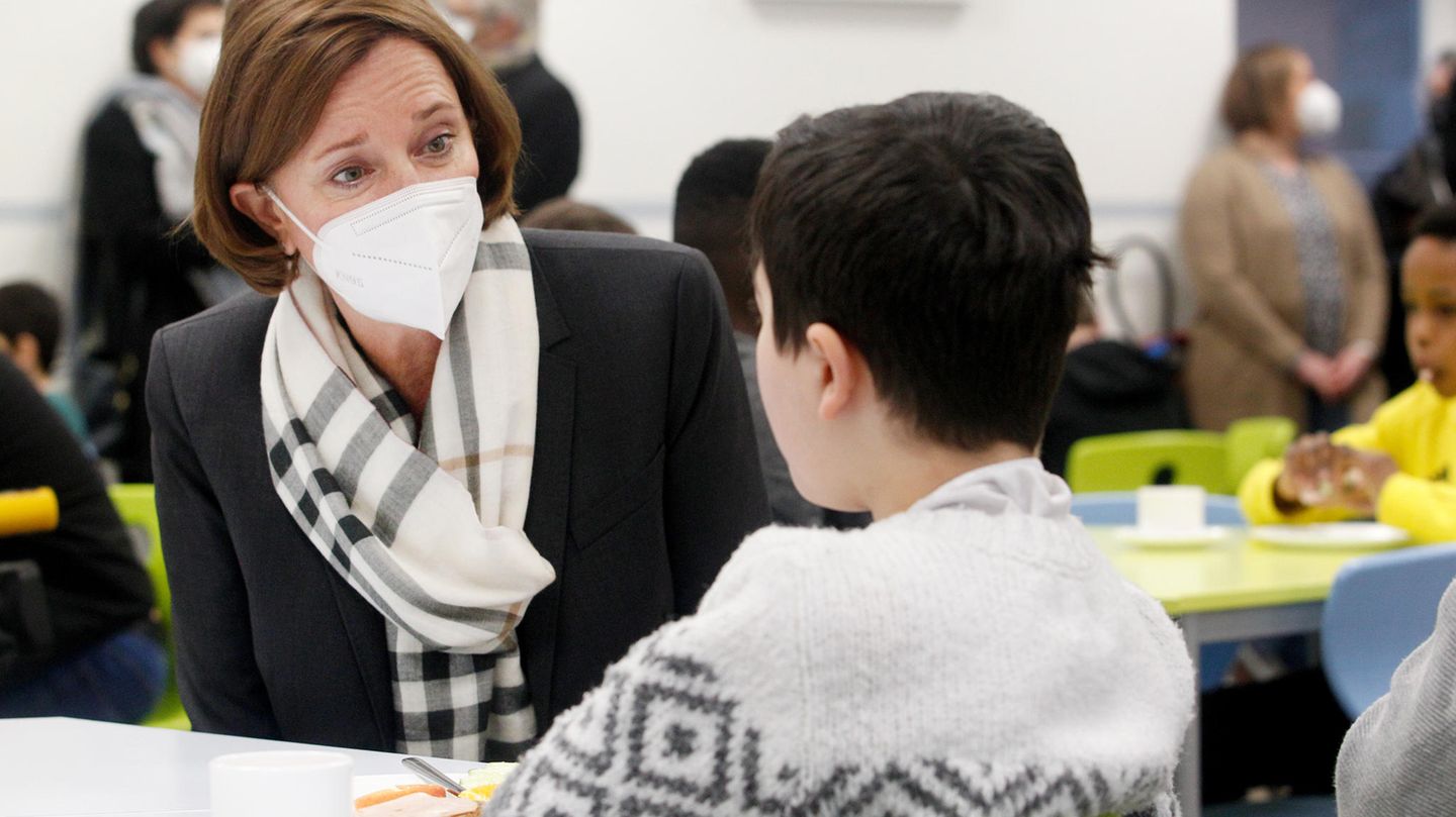 Yvonne Gebauer trägt eine Maske und spricht mit einem Kind