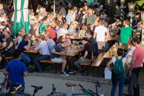 Bei sonnigem Wetter sitzen Menschen in München in einem Biergarten