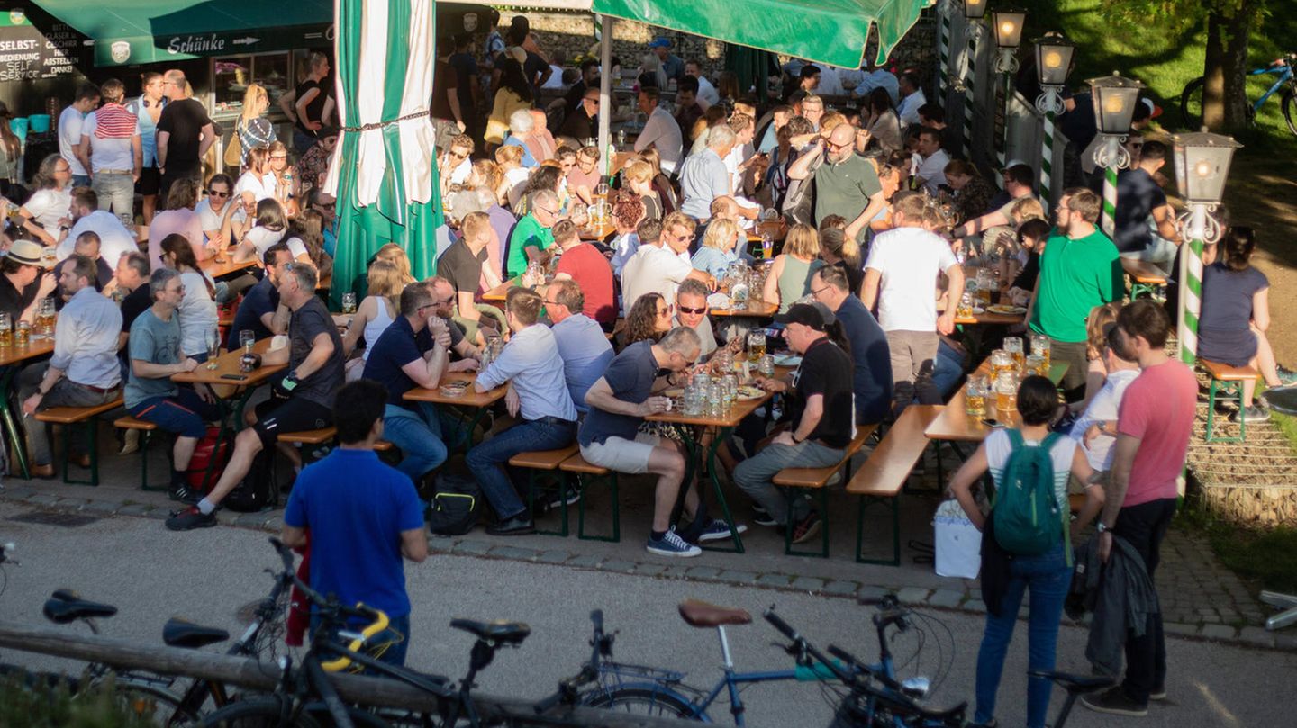Bei sonnigem Wetter sitzen Menschen in München in einem Biergarten