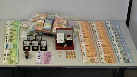 Beschlagnahmte Geldscheine, eine Uhr und Münzen sind auf einem Tisch im Polizeipräsidium Krefeld