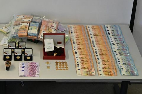 Beschlagnahmte Geldscheine, eine Uhr und Münzen sind auf einem Tisch im Polizeipräsidium Krefeld