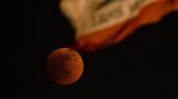 Der Blutmond bei der totale Mondfinsternis in El Monte in Kalifornien. Im Vordergrund weht die Flagge Kaliforniens mit dem Bär. 