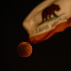 Der Blutmond bei der totale Mondfinsternis in El Monte in Kalifornien. Im Vordergrund weht die Flagge Kaliforniens mit dem Bär. 