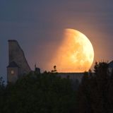 Ein hell erleuchteter Mond leuchtet bei der partiellen Mondfinsternis über einer Burg in Tschechien