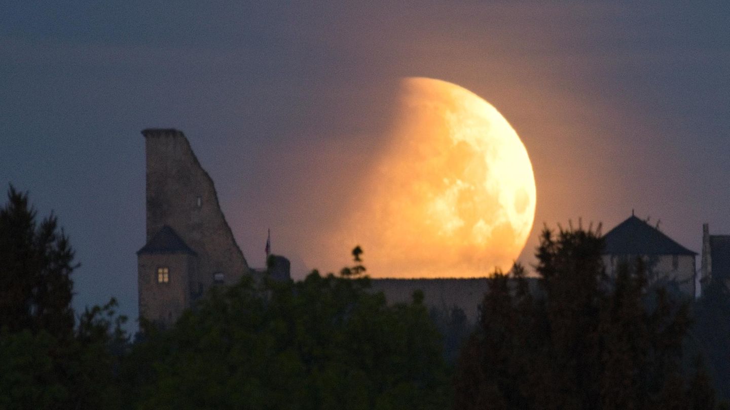 Ein hell erleuchteter Mond leuchtet bei der partiellen Mondfinsternis über einer Burg in Tschechien